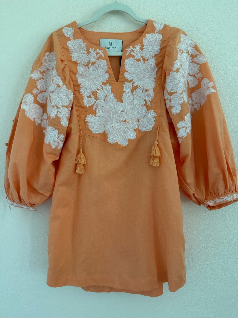 Blouse features split neckline with ties and voluminous embroidered puff sleeves